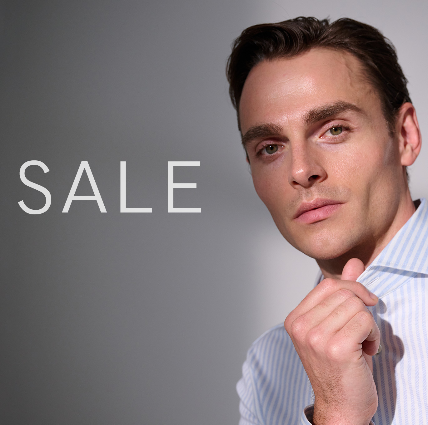 Modell trägt gestreiftes DESOTO-Hemd und greift in den Kragen – Bildteaser zum DESOTO Sale im Onlineshop