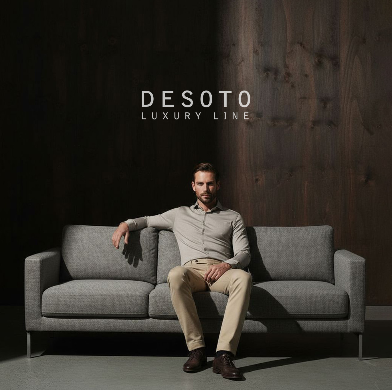 Modell sitzt auf grauem Sofa in Jersey-Hemd und beiger Hose – Teaser zur Luxury Line von DESOTO