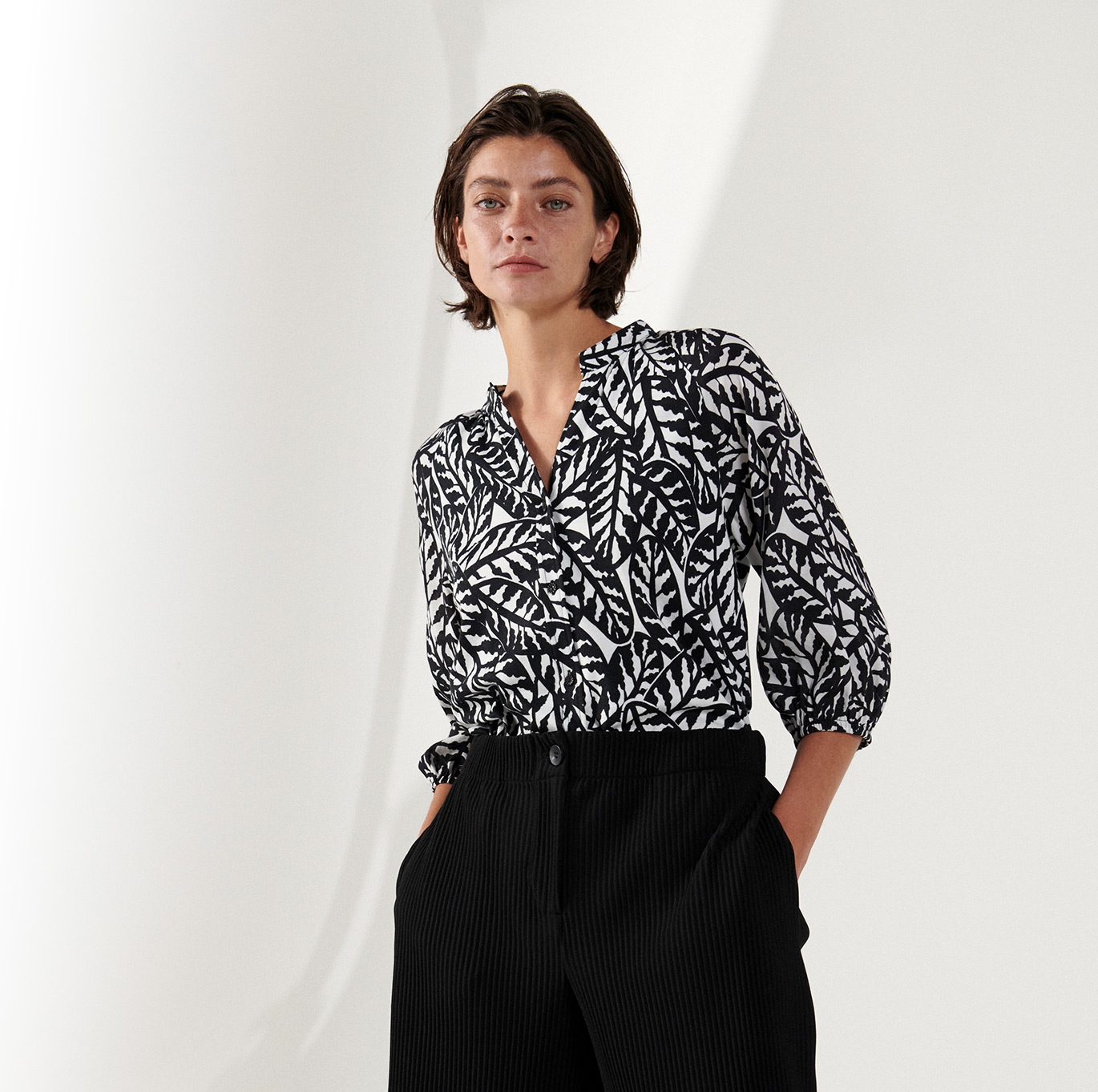 Frau in gemusterter Jersey-Bluse von DESOTO – moderner Look der Damenkollektion.